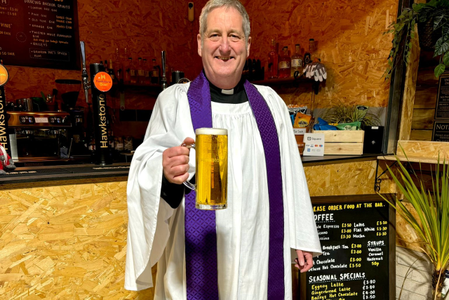 Rev Dave with a pint, inviting you to the weekend of festivities
